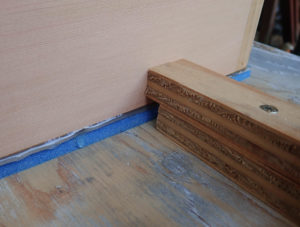 The lower tier of blocks is offset so as to not contact the adhesive. The upper tier of blocks hold cajon box in place.